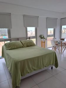 a bedroom with a large bed with a green blanket at Monoambiente con cochera en Puerto Norte in Rosario