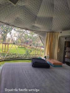 een bed in een tent met een groot raam bij ปีกุนรีสอร์ท & Swimming pool (Pigoon Resort) 