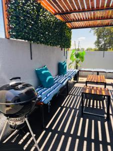 eine Terrasse mit einem Grill, Bänken und einem Tisch in der Unterkunft Zinathi Lodge in Lebowakgomo