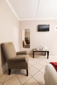 a living room with a chair and a table at Nongoma Lodge & Inn CC in Nongoma