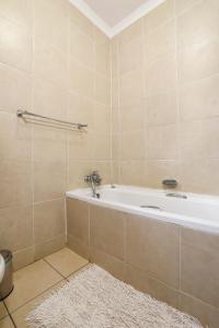 a bathroom with a tub and a white rug at Nongoma Lodge & Inn CC in Nongoma