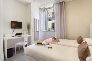 a hotel room with two beds and a desk at Hôtel P.L.M. in Cannes