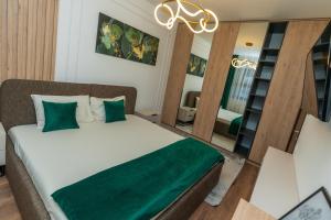 a bedroom with a bed with green sheets and a chandelier at Clăbucet Luxury Apartament in Predeal