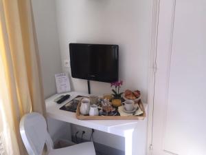 a desk with a tv and a table with a plate of food at Hôtel P.L.M. in Cannes