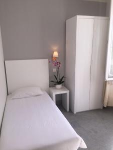 a bedroom with a white bed and a white cabinet at Hôtel P.L.M. in Cannes