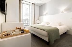 a white bedroom with a bed and a tray of food at Hôtel P.L.M. in Cannes