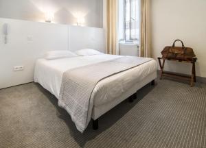 a bedroom with a large white bed with a brown bag on it at Hôtel P.L.M. in Cannes