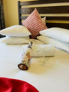 a bottle of wine and two glasses on a bed at Tribute Guest House Matala in Maseru