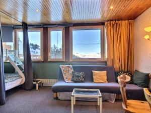 a living room with a blue couch and windows at Grand studio pour 3 personnes, au pied des pistes, tout proche des commerces avec Wifi - FR-1-455-166 in La Plagne