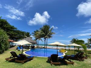 a swimming pool with chairs and umbrellas and the beach at Pousada Bahia Boa in Marau