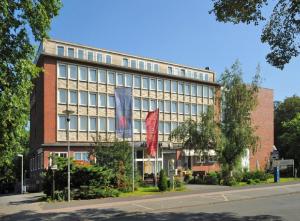 un bâtiment avec deux drapeaux devant lui dans l'établissement Retro - Art - Hotel Lünen, à Lünen