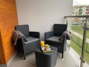 dwa krzesła i stół z tacą z jedzeniem na balkonie w obiekcie Apartament Majakowskiego DG w mieście Dąbrowa Górnicza