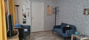 sala de estar con 2 sillas azules y TV en 1 rue des romains studio meublé clauss, en Niederbronn-les-Bains