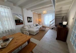 uma sala de estar com um sofá branco e uma mesa em L'Hirondelle Bleue - Classé 4 étoiles proche mer em Bourcefranc