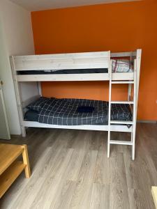 Ce lit superposé blanc se trouve dans un dortoir doté d'un mur orange. dans l'établissement Cozy Dutchie House Near Utrecht, à Nieuwegein