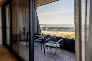 a balcony with a table and chairs and a view of the ocean at Kezand, Seaview beach apartment with cozy atmosphere in Cadzand