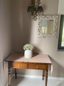 a vase of flowers on a table with a mirror at Casa de Prazeres in Prazeres