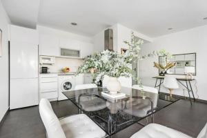 a white kitchen with a glass table and white chairs at New Heima Colon Square in Madrid