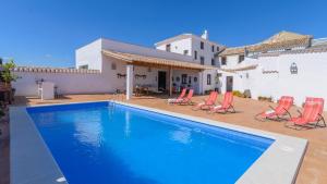 a swimming pool with red chairs and a house at El Molino de María Archidona by Ruralidays in Archidona
