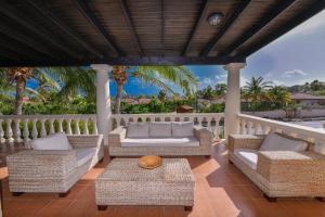 - une terrasse couverte avec des chaises en osier et une table dans l'établissement Tierra Del Sol Resort & Golf, à Palm-Eagle Beach