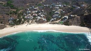 Cuatunalco的住宿－Centro Sati Bungalos，享有海滩的空中景致,设有房屋和海洋