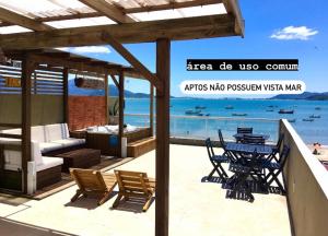 Un patio con mesa y sillas y el mar. en Villa das Flores - aptos 2 e 9, en Pinheira