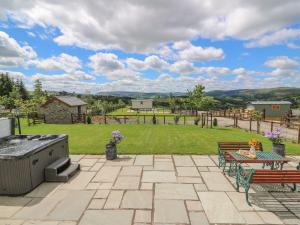 a patio with a grill and a table and benches at Hillside View in Rhayader