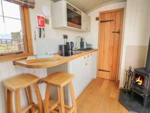 a kitchen with a stove and two stools in a tiny house at Ivy's Way in Rhayader