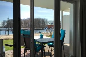 - une table et des chaises sur une terrasse avec vue sur l'eau dans l'établissement Hafennest Haus 6 Apartment 4, à Plau am See