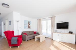 uma sala de estar com um sofá e uma cadeira vermelha em Leuchtturmblick Haus 6 A 5 em Plau am See