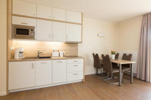 a kitchen with white cabinets and a table with chairs at Hafendorf Haus 5 Apartment 2 Nr25 in Plau am See