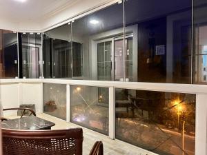 balcone con tavolo e alcune finestre in vetro di Home GRAMADO- 400 metros da Rua Coberta a Gramado