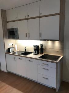 a kitchen with white cabinets and a sink and a microwave at Hafendorf Haus 5_ Apartment 3 in Plau am See +18 photos