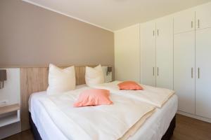 a bedroom with a large white bed with two pink pillows at Hafenperle P5A5 Nr37 in Plau am See