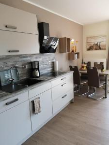 una cocina con armarios blancos y una mesa con sillas. en 2 Zimmerapartment 2 Terrassen P7a1 en Plau am See