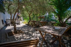 a wooden table and benches in a patio with trees at Apartments and Rooms Marino in Trogir