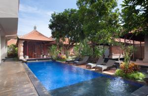 a swimming pool with chairs and a house at Nesa Sanur Bali in Sanur