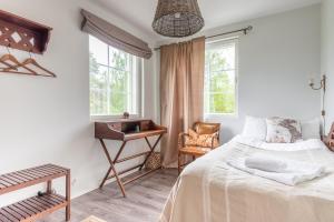 a bedroom with a bed and a desk and windows at Villa Jokivarsi Bed & Breakfast in Vantaa