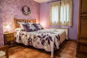 a bedroom with purple walls and a bed and a window at Apartamentos Cruz Mar in Poveda de la Sierra