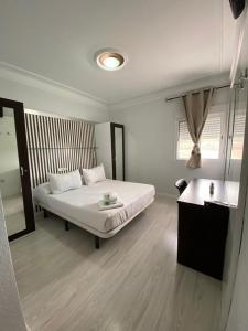 Habitación blanca con cama y espejo en Hostal Fuente del Pino, en Jumilla