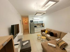 ein Wohnzimmer mit Couch und Küche in der Unterkunft Barak Royal Suites 52 garden - חמש דקות מהים ומהטיילת in Eilat