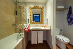 a bathroom with a sink and a toilet and a mirror at Estival Islantilla in Islantilla