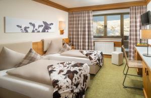 a hotel room with two beds and a desk at Hotel-Pension Schattberg in Saalbach Hinterglemm