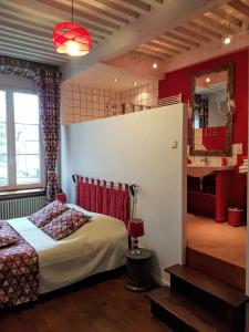 a bedroom with a bed in a room with red walls at Maison d'Eusébia in Château-Chalon