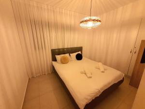 ein Schlafzimmer mit einem Bett mit weißen Laken und einem Kronleuchter in der Unterkunft Barak Royal Suites 52 garden - חמש דקות מהים ומהטיילת in Eilat + 28 Fotos