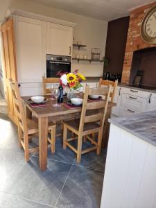 a kitchen with a wooden table and chairs with flowers on it at The Nook Cosby Village 