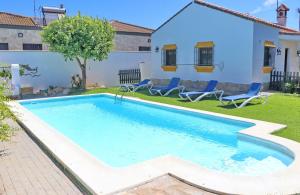 a swimming pool in a yard with chairs and a house at Chalet la Dehesa in Conil de la Frontera