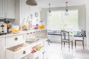 a kitchen with white cabinets and a table and chairs at Villa Jokivarsi Bed & Breakfast in Vantaa