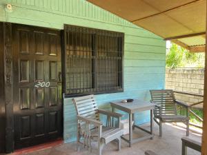 un porche con 2 sillas, una mesa y una puerta en Westport Cottage en Negril