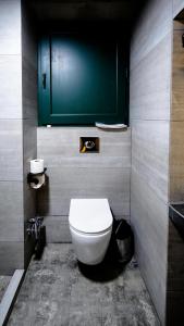 a bathroom with a white toilet and a green door at Anbani Apartments - City Center in Tbilisi City